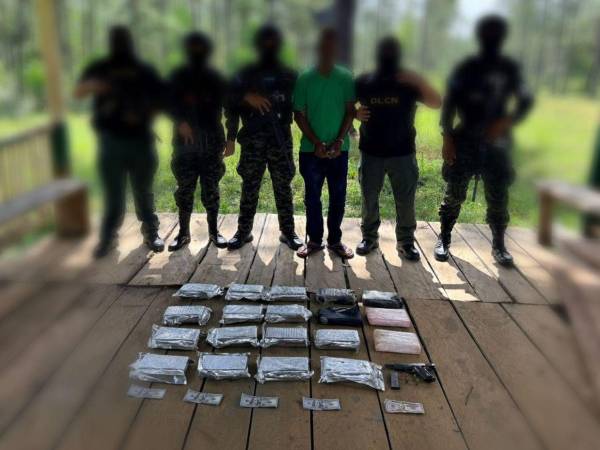 El detenido es custodiado por efectivos militares, junto a la evidencia de los 19 kilos de cocaína, el dinero y el arma de fuego.