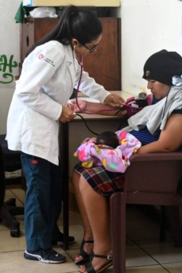 Sosteniendo a su bebé, una mujer con síntomas de fiebre del dengue recibe atención médica en el Centro de Salud Alonso Suazo en Tegucigalpa, Honduras. Foto: Agencia AFP.