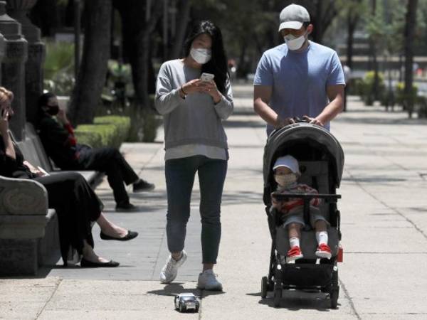 Una familia porta mascarillas para protegerse del coronavirus en la Ciudad de México, el lunes 27 de abril de 2020. (AP Foto/Marco Ugarte)