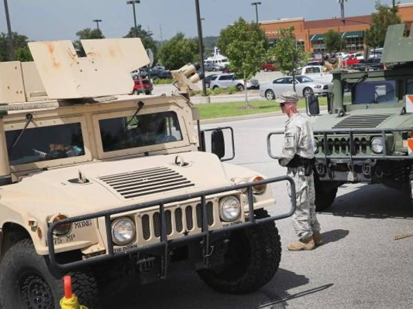 Un efectivo de la Guardia Nacional en medio de dos autos blindados.
