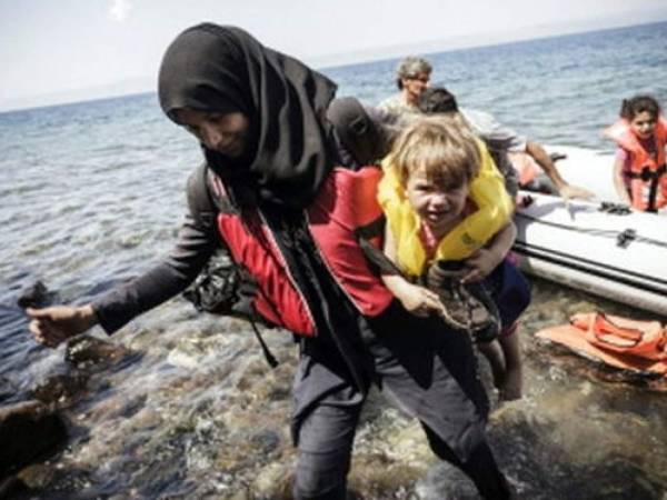 Una mujer siria con su hijo llega a la isla griega de Lesbos, después de cruzar el mar Ego en un bote inflable desde Turquía.