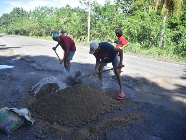 Los tramos más dañados de la carretera CA-13 se encuentran entre La Ceiba y Trujillo, donde jóvenes han tapado baches con mezcla de cemento. En varios kilómetros el asfalto ha desaparecido.