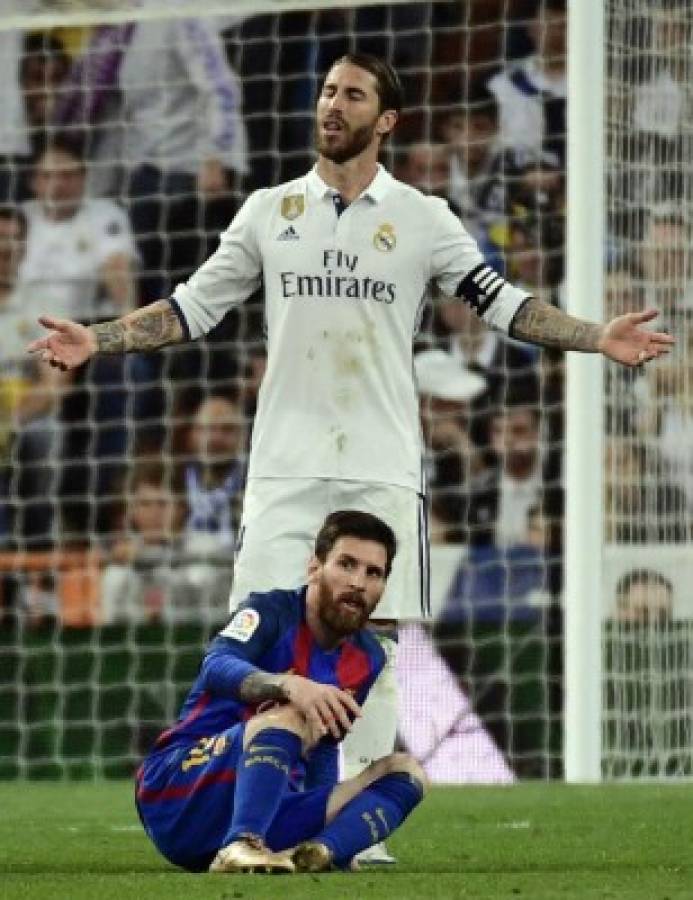 Real Madrid's defender Sergio Ramos (top) gestures beside Barcelona's Argentinian forward Lionel Messi during the Spanish league football match Real Madrid CF vs FC Barcelona at the Santiago Bernabeu stadium in Madrid on April 23, 2017. / AFP PHOTO / PIERRE-PHILIPPE MARCOU