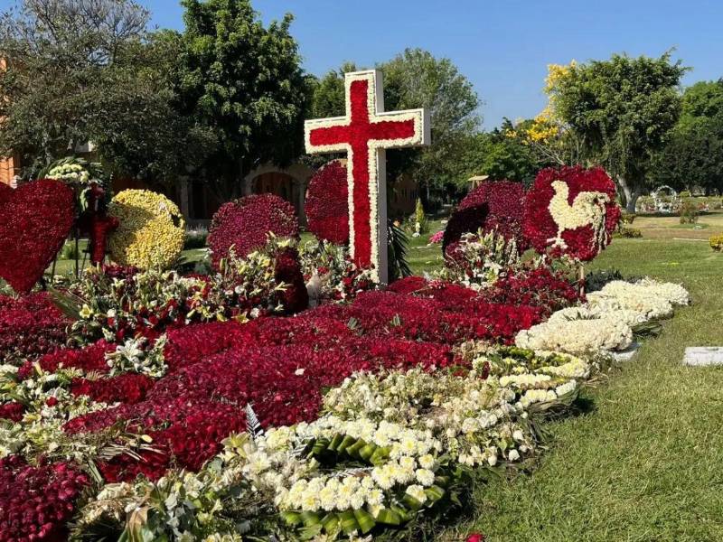 En medio de arreglos florales de gran tamaño y con figuras de cruz, corazones y gallos descansa El Mencho.