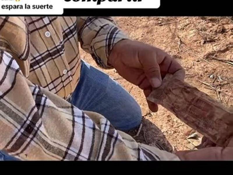 Uno de los buscadores muestra el billete de un lempira hallado en la billetera del hondureño.