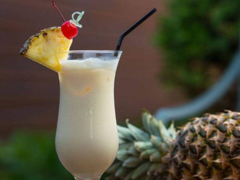 La piña colada, un icónico cóctel, asociado con playas de arena blanca y aguas cristalinas, símbolo caribeño.