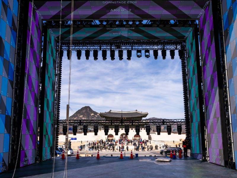 Varias personas caminan cerca del escenario principal para presenciar un concierto gratuito del grupo de K-pop BTS en la plaza Gwanghwamun de Seúl, Corea del Sur.