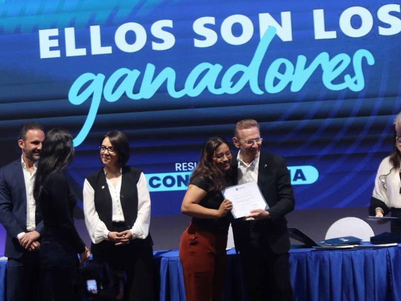 El presidente Fredy Nasser hace entrega del certificado de beca a uno de los jóvenes beneficiados.