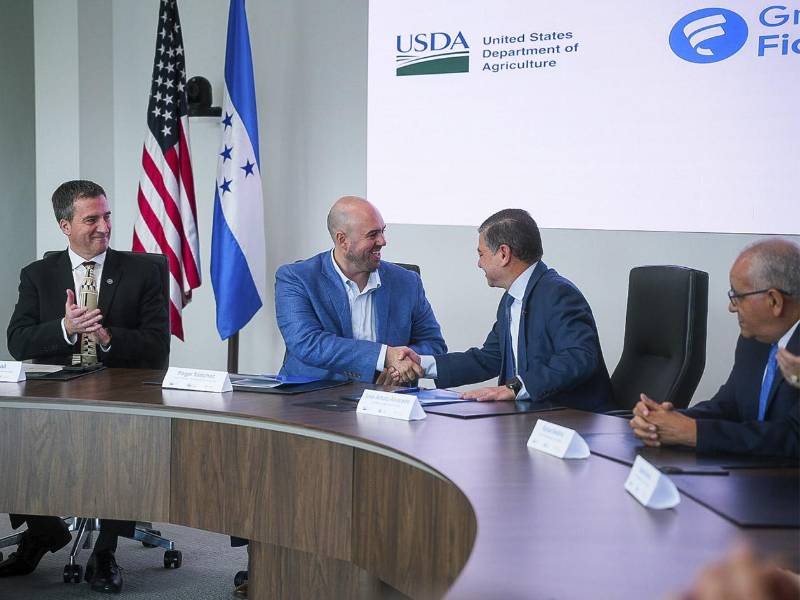 Representantes de Grupo Ficohsa y Partners of the Americas estrechan la mano tras la firma del acuerdo, simbolizando una alianza que impulsará la educación, la nutrición infantil y el desarrollo sostenible.