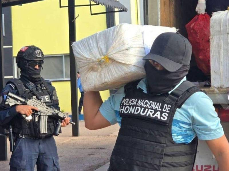 Un agente policial traslada parte de la evidencia decomisada durante el operativo contra estructuras dedicadas al narcotráfico en El Progreso, Yoro.