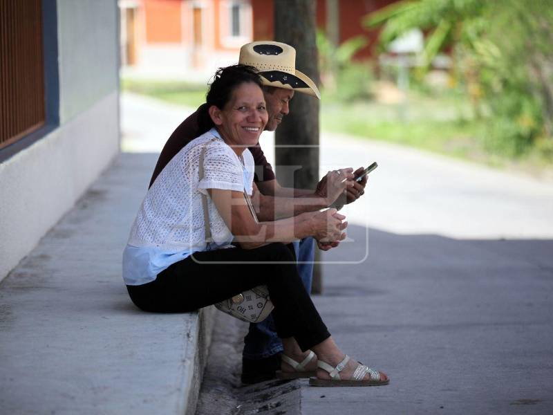 Una pareja aguarda en la acera de una casa, en espera del bus que los tarería a la capital, Tegucigalpa.