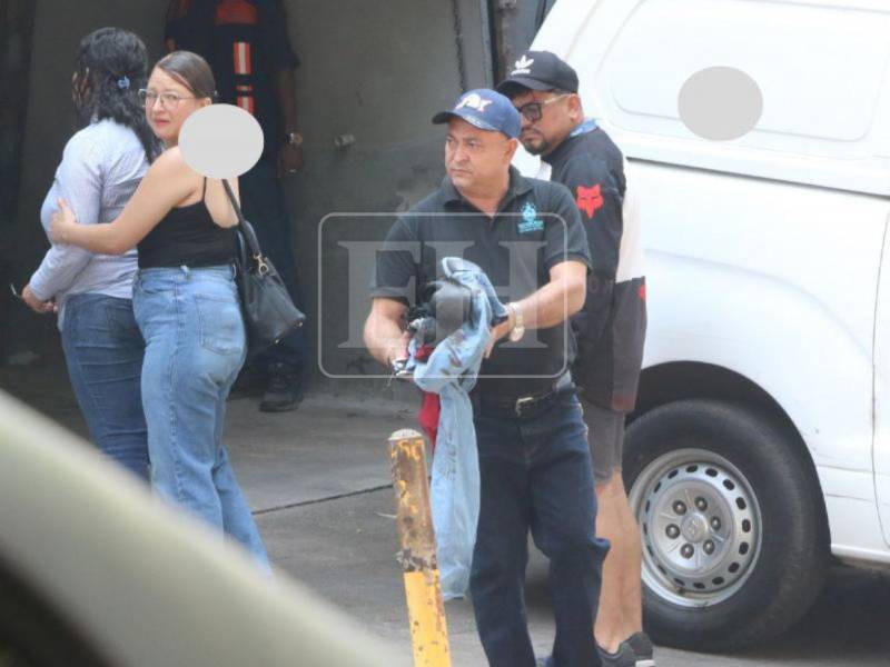 Don Samuel Juárez carga la ropa que su hijo José Manuel llevaba puesta ayer, mientras sus parientes retiran el cadáver de su vástago, en la morgue.