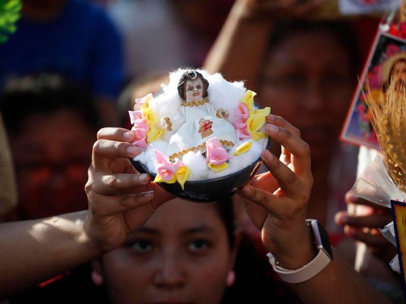 Una mujer muestra una pequeña escultura del Niño Jesús, durante la procesión.