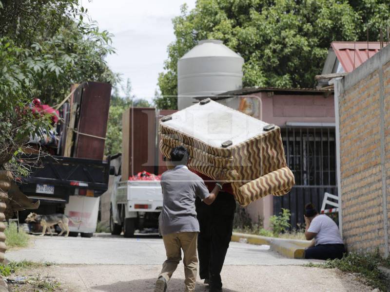 Dos hombres cargan un mueble para subirlo a los vehículos que llegaron para hacer la mudanza obligada d eestas familias.