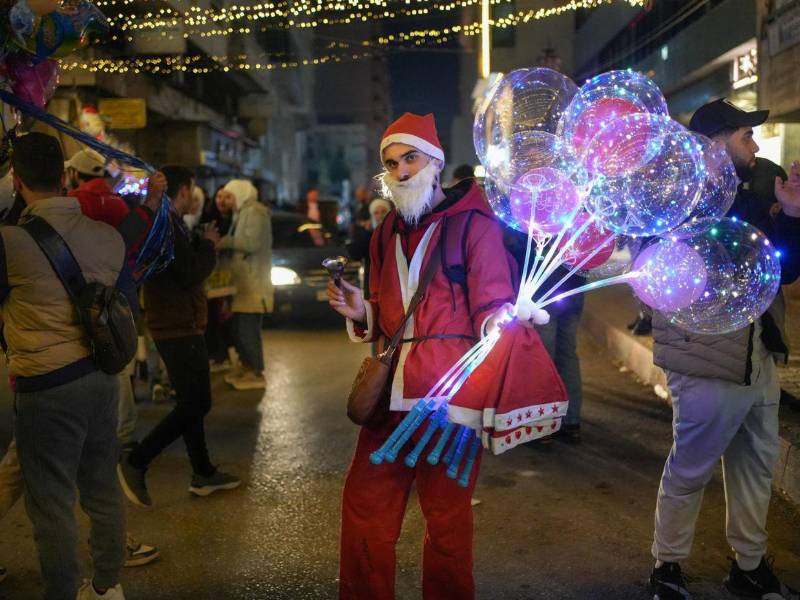 Un hombre vestido como Papá Noel sostiene globos este miércoles, durante las celebraciones navideñas en Lakatia (Siria). Los cristianos de Siria celebran el nacimiento de Cristo un año después de que Bashar Assad huyera y la oposición siria tomara el control del país.