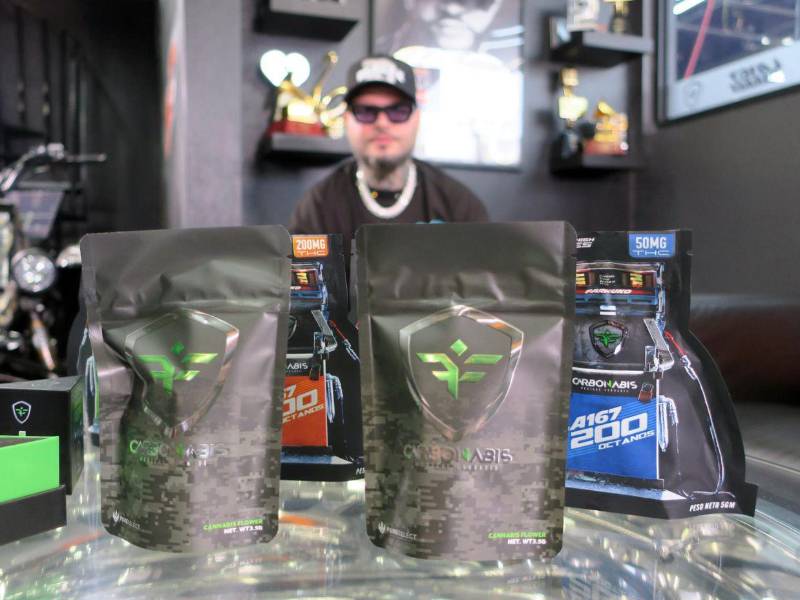 El artista urbano puertorriqueño Farruko posa frente a varios paquetes de su línea de cannabis medicinal durante una entrevista con EFE.