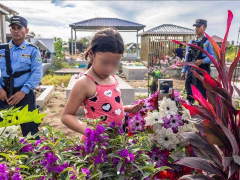La imagen muestra la visita de Julia López, de nueve años, a la tumba de su padre, Juan López, un defensor ambiental hondureño.