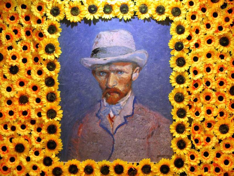 En una sala se muestra un retrato del autor rodeado de girasoles.