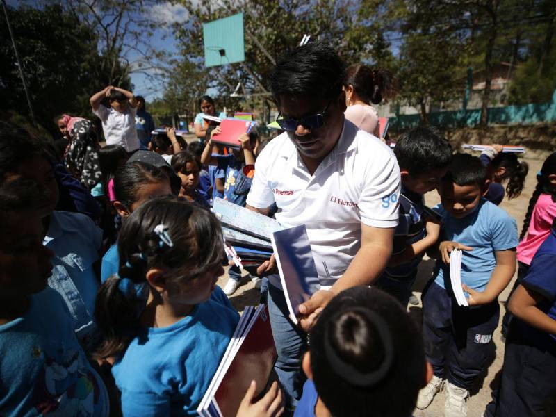 El periodista de EL HERALDO, Marbin López, entrega los cuadernos a los niños de la Escuela Israel Muñoz Franco, en la aldea Las Cañadas, Valle de Ángeles.