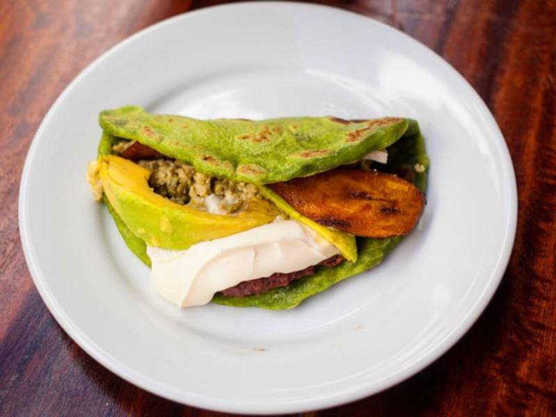 La baleada con tortilla de espinaca puede acompañarse con los ingredientes tradicionales, como frijoles fritos, huevo, plátano maduro, aguacate y mantequilla crema.