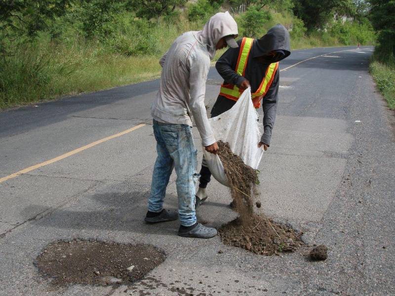 Estos dos jóvenes madrugan para tapar baches, ayudar a evitar accidentes y ganarse unos lempiras.
