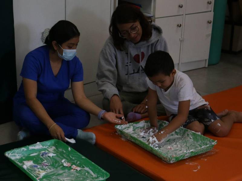 Jessica acompaña a su hijo Mateo mientras interactúa y juega con espuma.