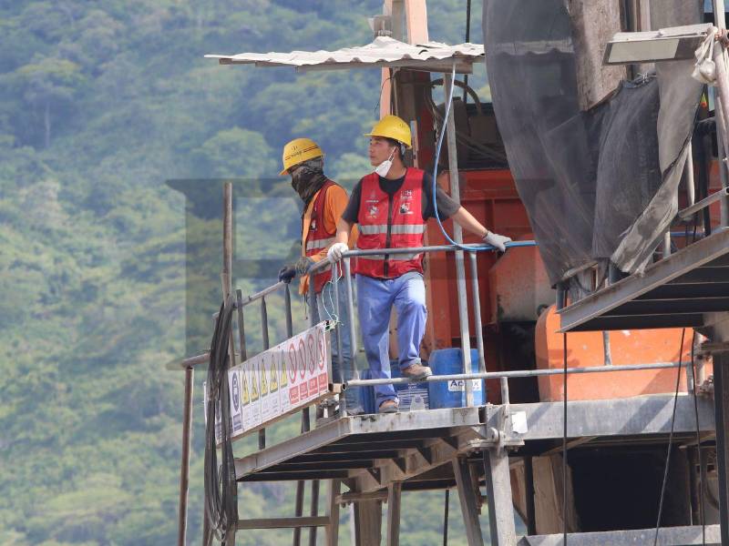 Dos trabajadores chinos observaban desde una torre a los otros empleados. El hombre con la mascarilla le gritaba a un hondureño que abriera o cerrara una llave con agua.