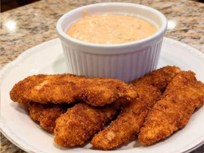 Dedos de pollo: Se trata de crujientes tiras de pollo empanizado, doradas a la perfección, acompañadas de salsa tártara con sriracha.