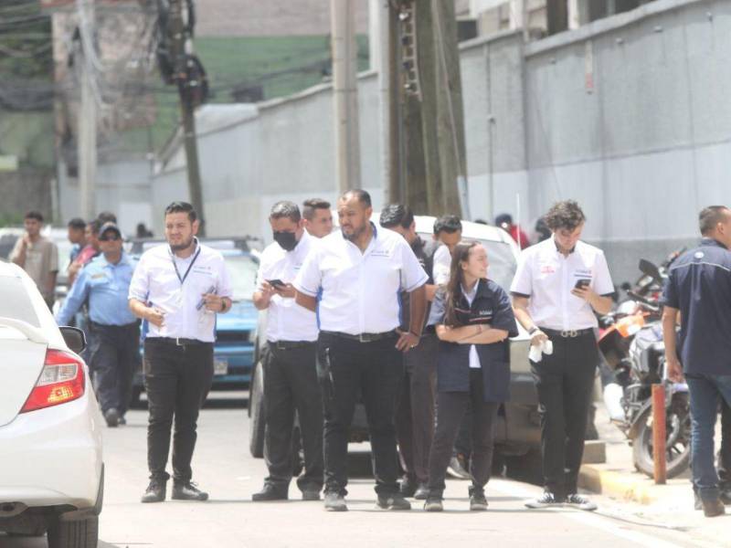 Empleados de diferentes empresas observaban el incendio tras ser evacuados por las autoridades para reducir el riesgo de víctimas.