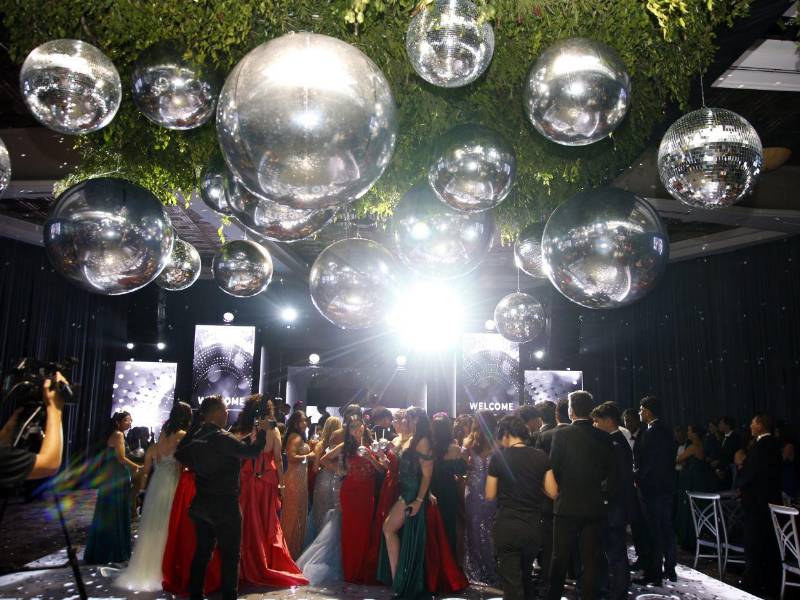 La ambientación fue concebida por la planner Virginia Cárcamo, quien integró luces LED, detalles en neón, lentes luminosos y esferas de espejos para crear un espacio dinámico y visualmente impactante.