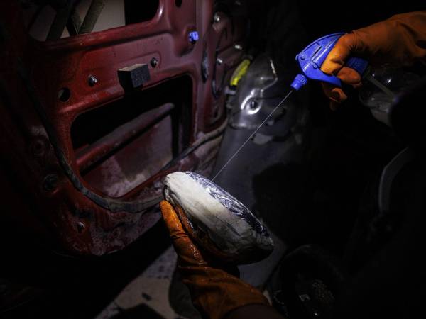 Un paquete es rociado con un líquido de sustancias químicas que ayudan a disimular el potente olor a fentanilo. (Adriana Zehbrauskas para The New York Times)