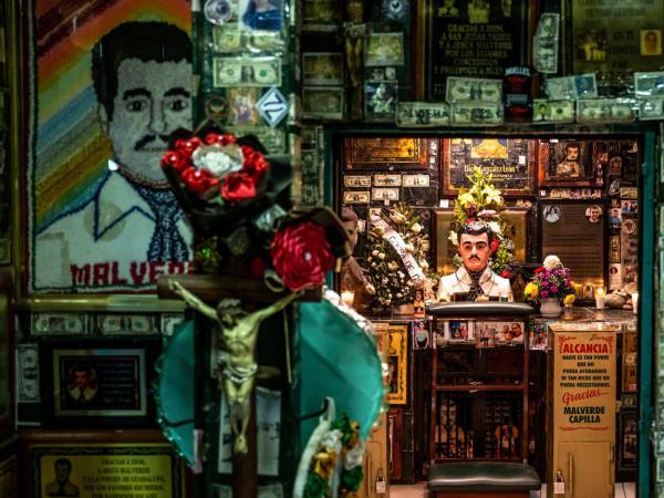 Ofrendas de flores, velas, fotos y billetes de dólar en un santuario dedicado a Jesús Malverde, un narcosanto, en Culiacán, México, el 25 de noviembre de 2024.