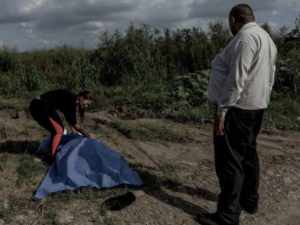 Juani Andrade cubre el cuerpo de su primo José Carlos Sazueta con una tela proporcionada por Ramón Soto (der.), un trabajador funerario de Culiacán, Sinaloa.