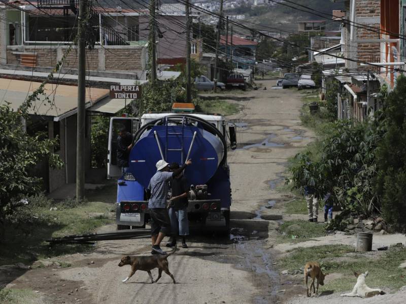 Una cisterna privada abastece a los residentes en una de las calles polvorientas de la colonia José Trinidad Cabañas. Depender de este servicio particular representa para los hogares de la periferia un costo de entre 50 y 100 lempiras por barril, un gasto obligatorio ante la falta de red pública en las zonas altas.