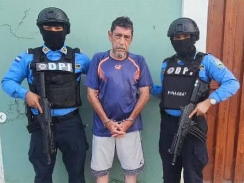 <i>En la fotografía aparece Perfecto Jesús Enamorado flanqueado por dos agentes de la Dirección Policial de Investigaciones (DPI) armados y encapuchados. Imagen tomada de las redes sociales el día de su captura. Foto: cortesía Proceso Digital.</i>