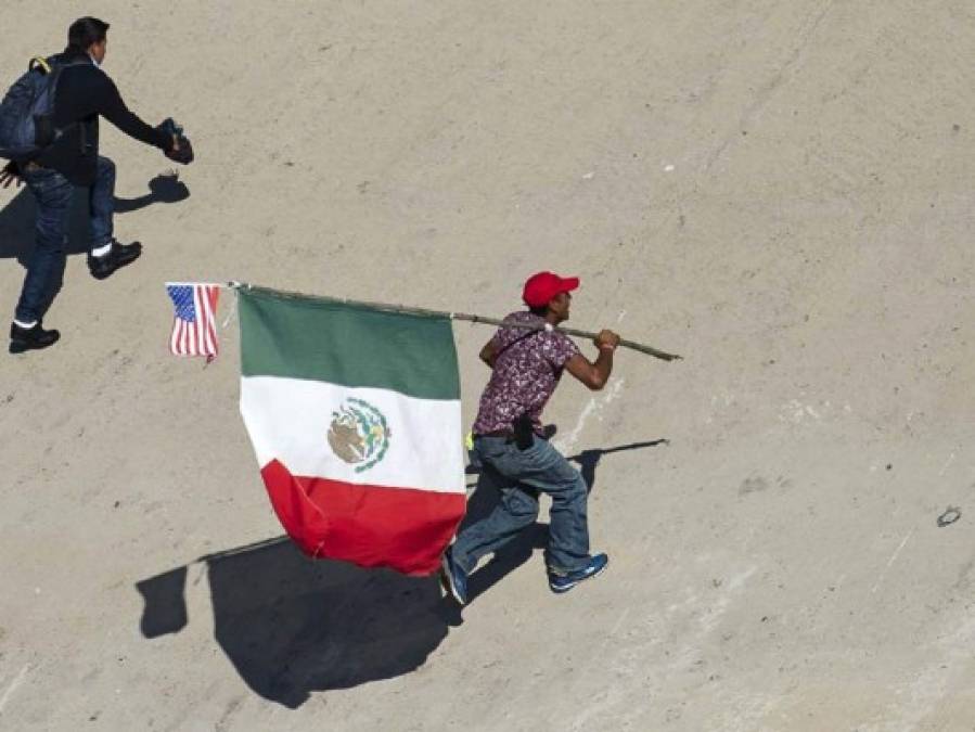 Fotos del momento en el que migrantes de la caravana saltaron valla fronteriza de Estados Unidos, pero fueron detenidos con gases lacrimógenos