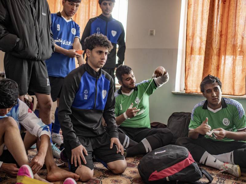 Young futsal players, including Hamza Qasimi, center, listen to a coach discuss strategy before a game in a southeastern neighborhood of Kabul, Afghanistan, Nov. 28, 2025. A triumph in indoor soccer has turned Alireza Ahmadi, 17, and other players from the Hazara minority, long marginalized in Afghanistan, into national heroes.
