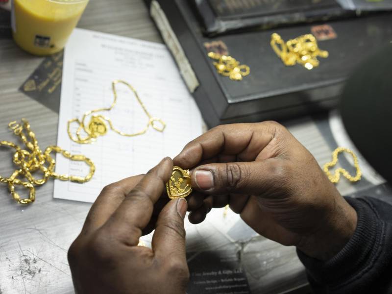 Un empleado examina joyas matrimoniales chinas que una clienta vendía en Bullion Exchanges en Nueva York.