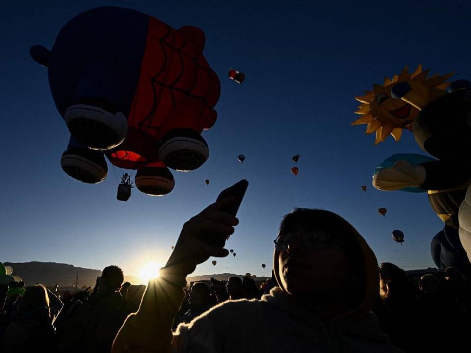 Los espectadores toman fotografías mientras el globo aerostático Spider Pig despega al amanecer durante la Fiesta Internacional de Globos de Albuquerque en Albuquerque, Nuevo México, donde están esperando observar el eclipse anular.