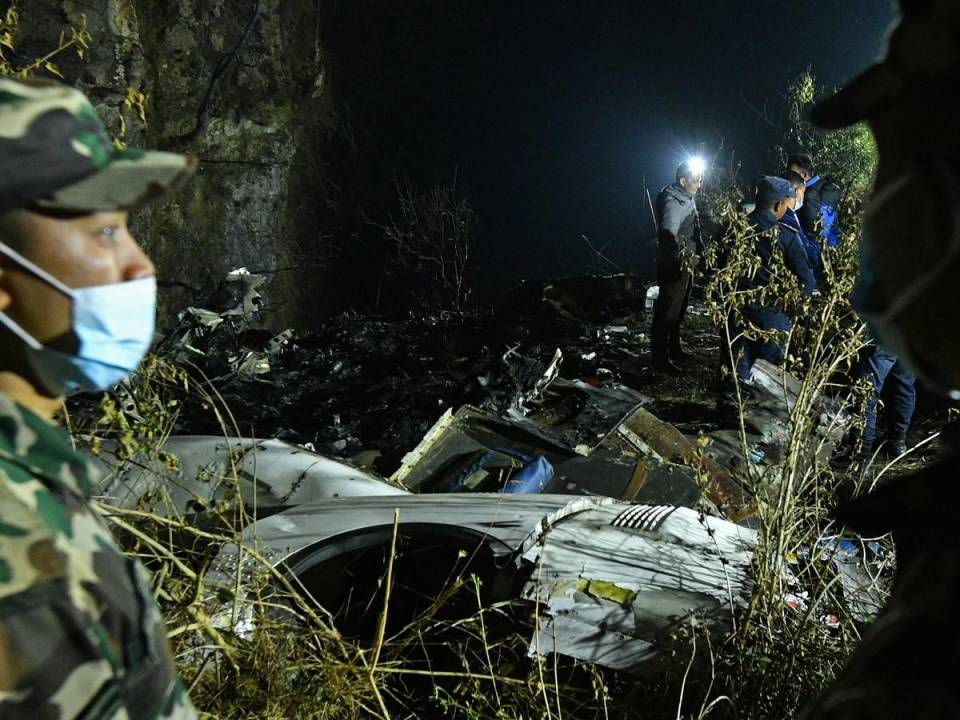 Los rescatistas inspeccionan los restos en el lugar donde se estrelló un avión en Pokhara.