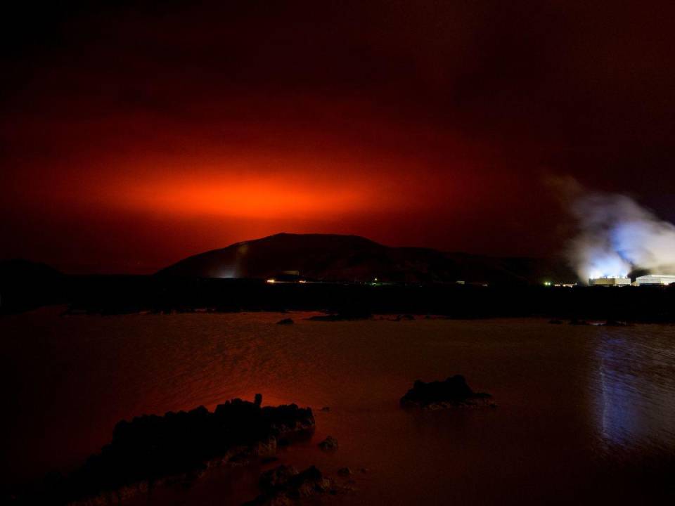 El brillo rojo del magma que fluye desde el volcán Fagradalsfjall en erupción detrás de la emblemática Laguna Azul, a unos 45 km al oeste de la capital de Islandia, Reykjavik, el 19 de marzo de 2021.