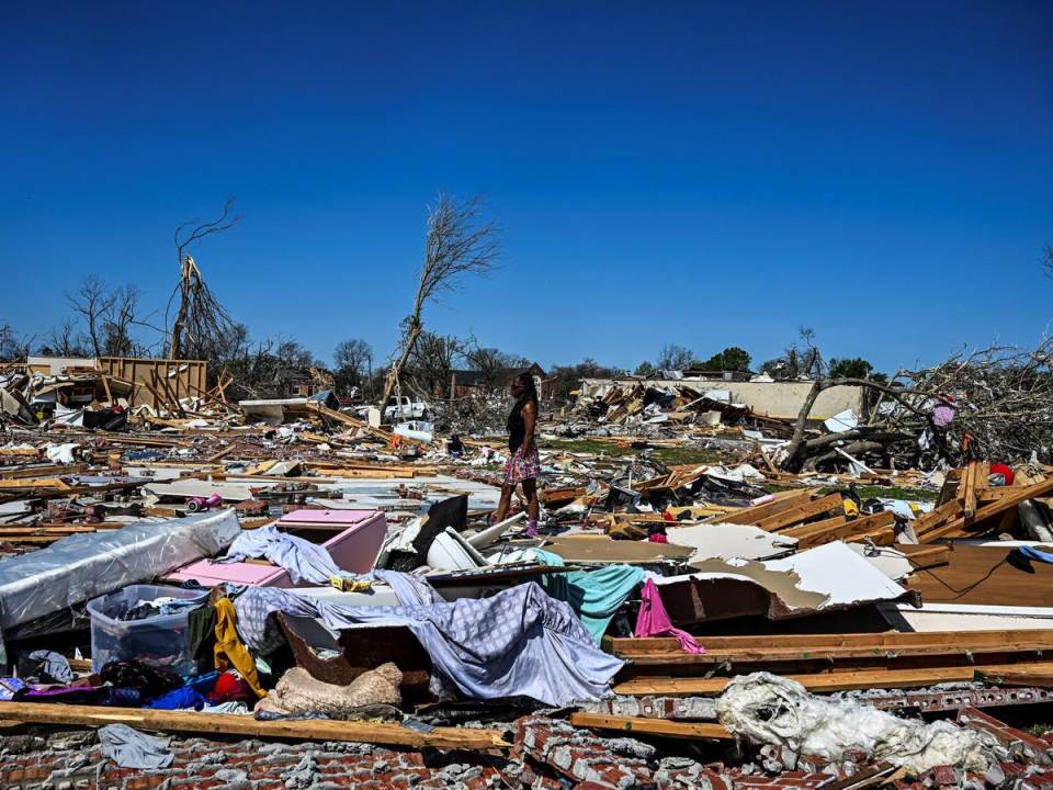 Una mujer camina entre los restos de una casa en Rolling Fork, Mississippi, luego de que un tornado azotara el área, el 26 de marzo de 2023.