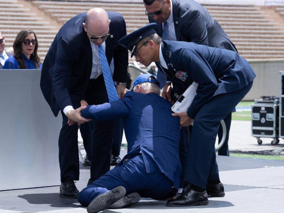 Momento en que Joe Biden es levantado por los oficiales presentes, luego de tropezarse con un objeto que se encontraba en el podio.