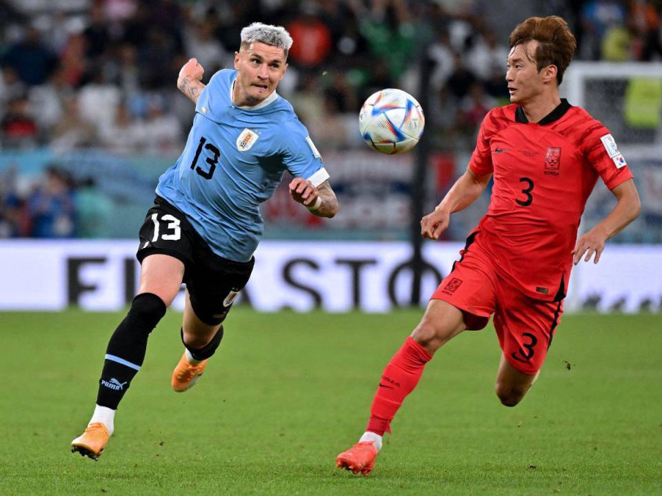 El defensor número 13 de Uruguay, Guillermo Varela, y el defensor número 03 de Corea del Sur, Kim Jin-su, corren con el balón durante el partido de fútbol del Grupo H de la Copa Mundial de Qatar 2022 entre Uruguay y Corea del Sur en el Education City Stadium en Al-Rayyan, al oeste de Doha, en noviembre. 24 de febrero de 2022.