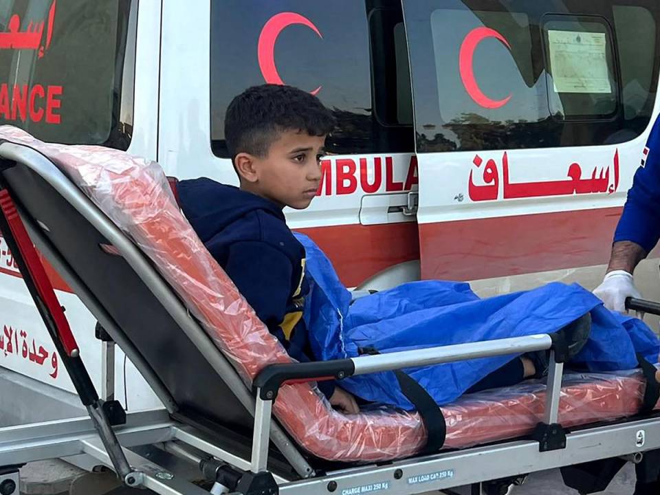 Un niño palestino herido es llevado a una ambulancia en el cruce fronterizo de Rafah en Egipto después de ser evacuado de la Franja de Gaza, el 25 de diciembre de 2023
