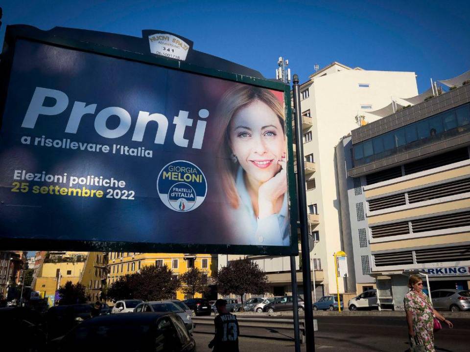 Los peatones pasan frente a un cartel electoral de Giorgia Meloni, líder de extrema derecha del partido Hermanos de Italia.