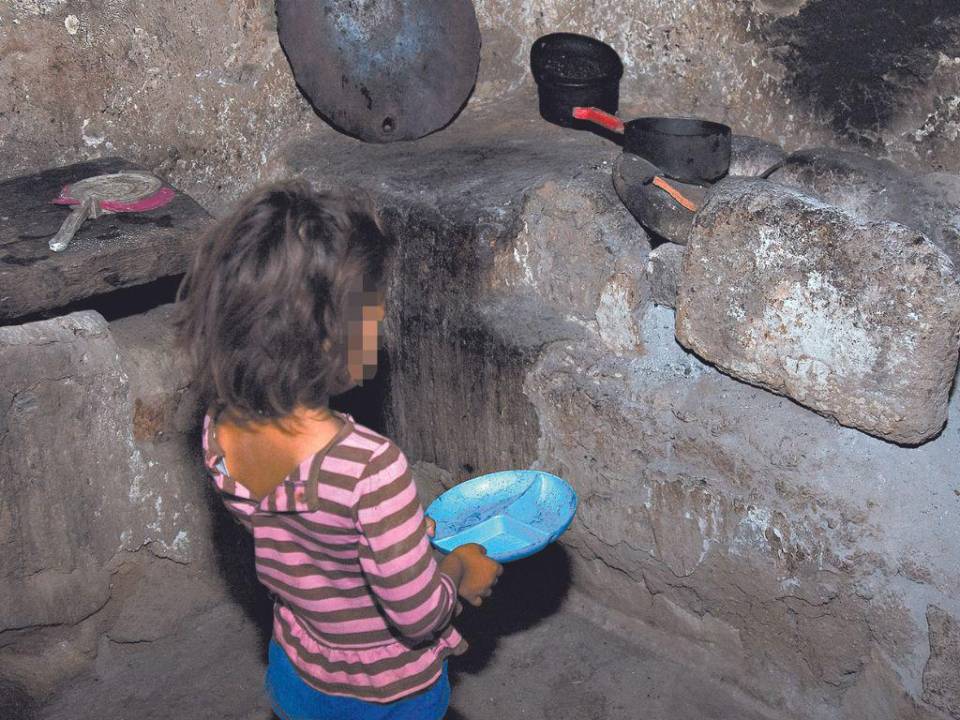 Una niña con hambre en el corredor seco se da cuenta que en la cocina de su deteriorada vivienda no hay alimentos.