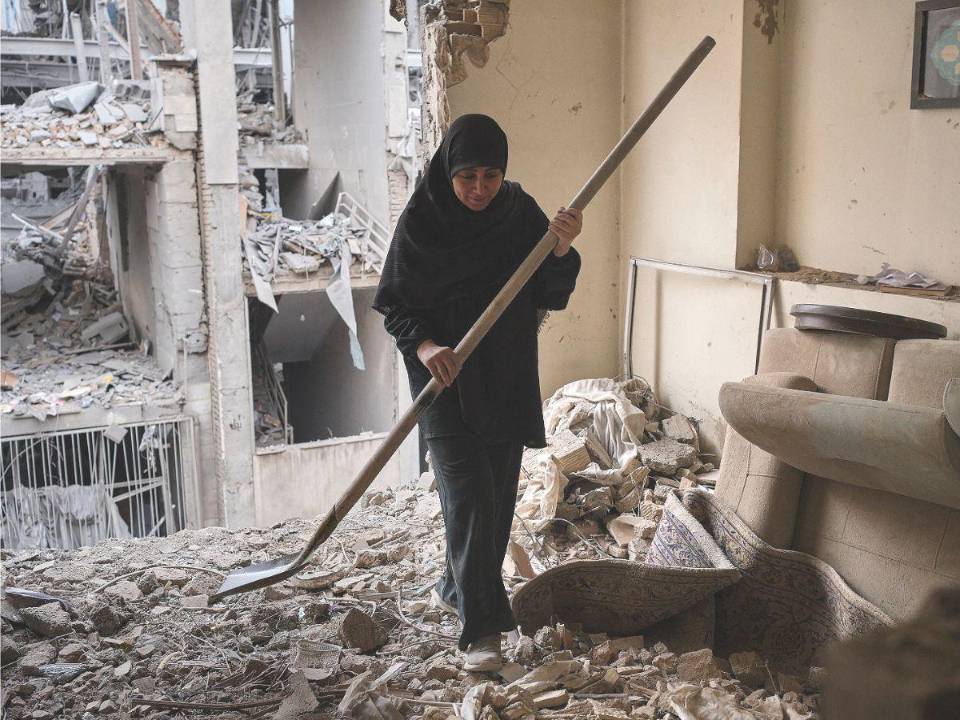 Economía. Una mujer trata de limpiar una vivienda en el barrio de Haft Chenar de Teherán que resultó dañada en un ataque de Estados Unidos e Israel. La guerra, que cumplió ayer 17 días, está asfixiando la economía de los iraníes y poniendo contra las cuerdas a numerosos negocios.