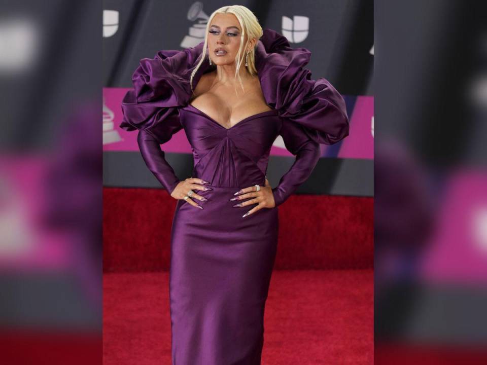 Christina Aguilera eligió un vestido morado para posar en la alfombra roja de los premios Grammy Latinos 2022. Con gran escote y volúmenes en los hombros, es un diseño de Zac Posen.