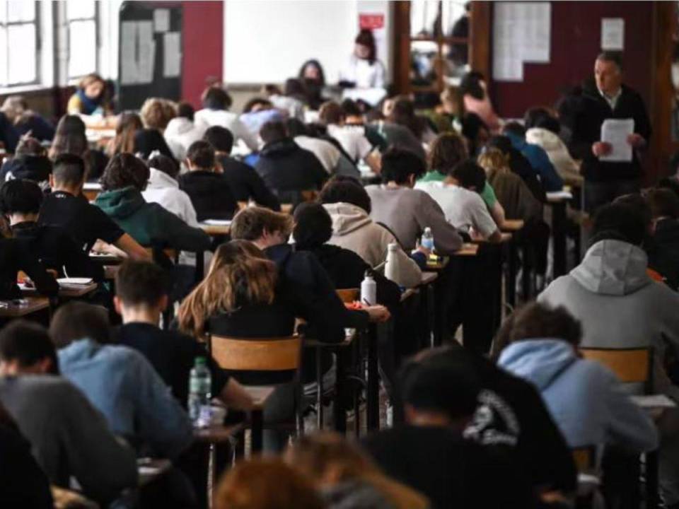 Estudiantes realizan un examen mientras su profesor los supervisa.